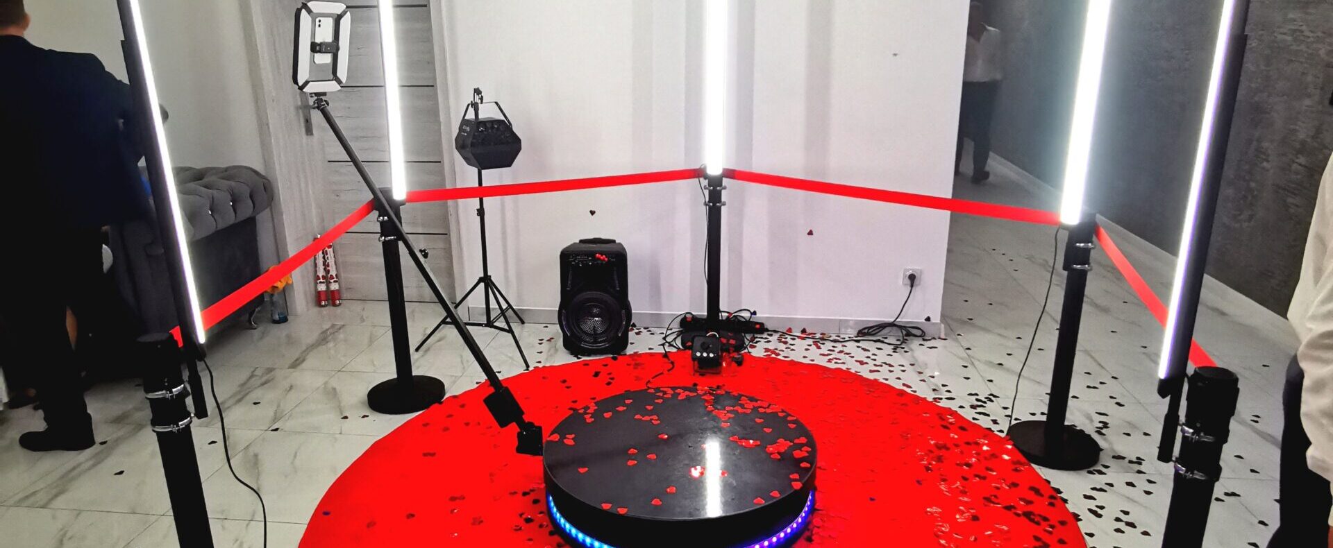Video Booth 360 – the platform on a red carpet strewn with confetti in a white room
